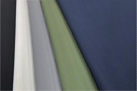 A close-up photo of a piece of a fabric with many droplets of water on it. The fabric is brown with a red stripe.